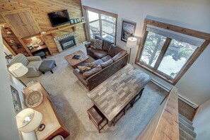 A spacious living area with a fireplace, a large window, and a television mounted on the wall.