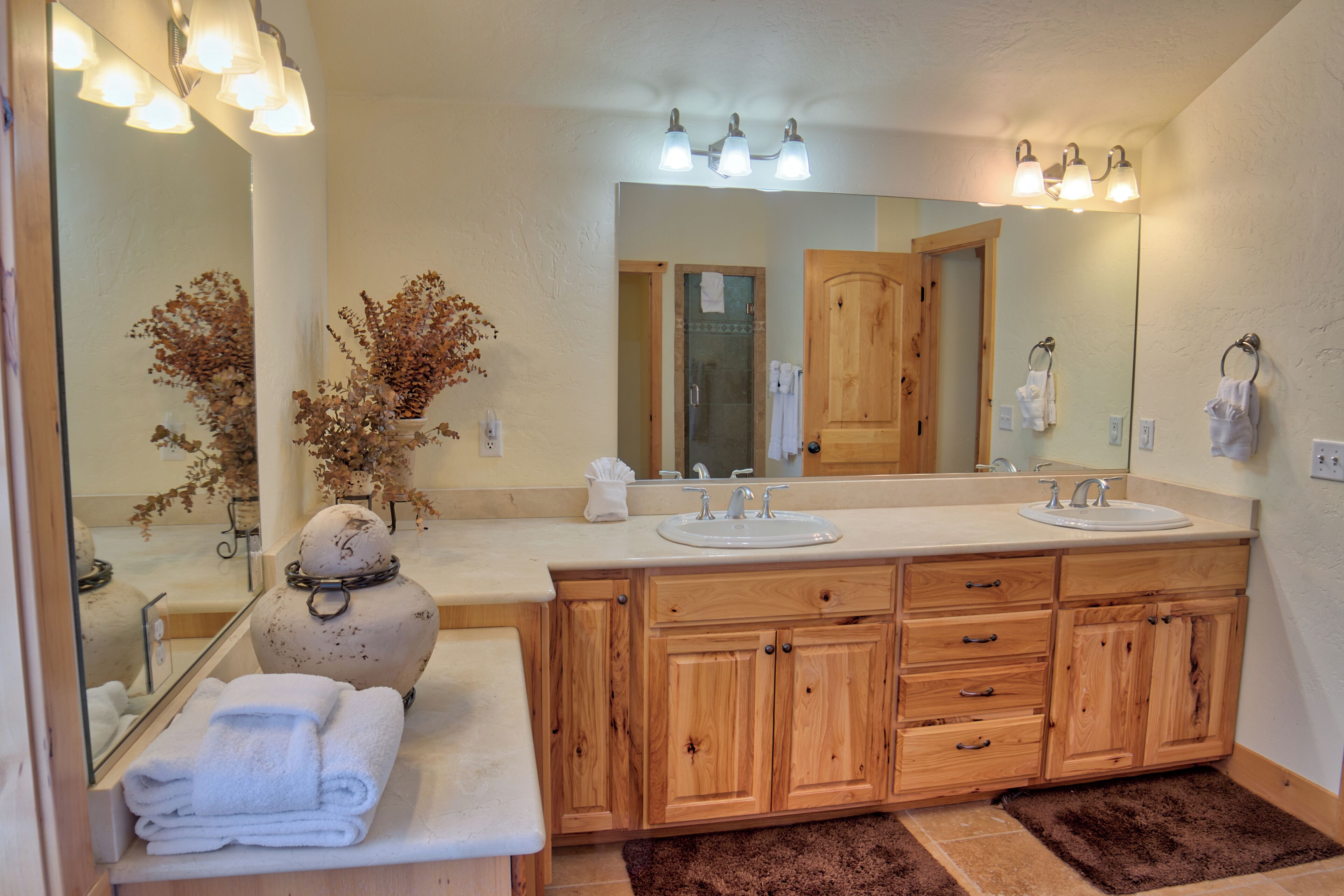 A bathroom with wooden cabinets, a large mirror, and two sinks.