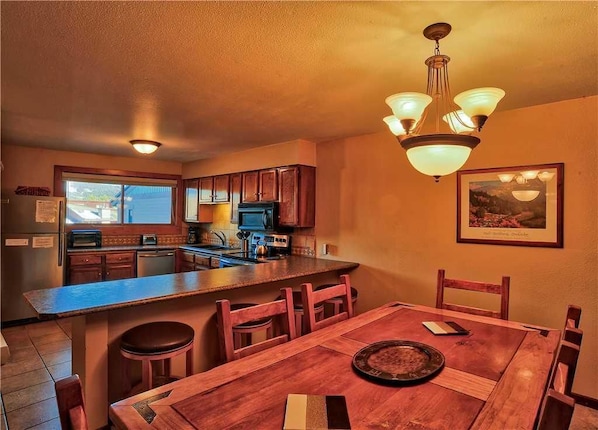A kitchen with wooden cabinets, a dining table, and a bar area.