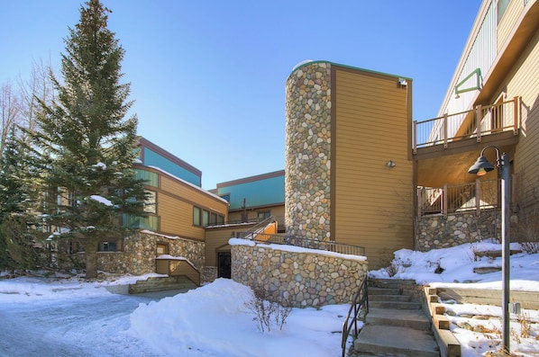 Un edificio con fachada de piedra, entrada de madera y suelo cubierto de nieve.