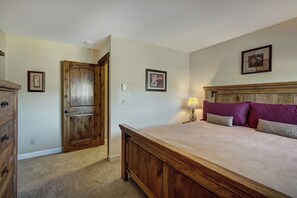 A bedroom with a wooden bed, a nightstand, a lamp, and two framed pictures on the wall.