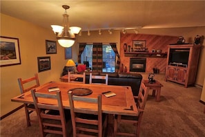A cozy living room with a wooden dining table, leather sofa, and a fireplace.
