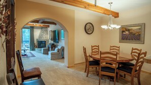 A dining area with wooden chairs and a table, a fireplace, and a clock on the wall. - Ten Mile Suites 103 Downtown Condos with On-site Hot Tub (Breckenridge)