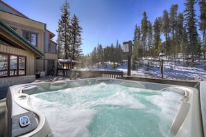 A hot tub with a view of a snowy landscape and a building with large windows.