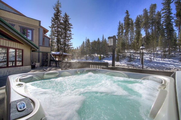 Un bain à remous avec vue sur un paysage enneigé et un bâtiment doté de grandes fenêtres.