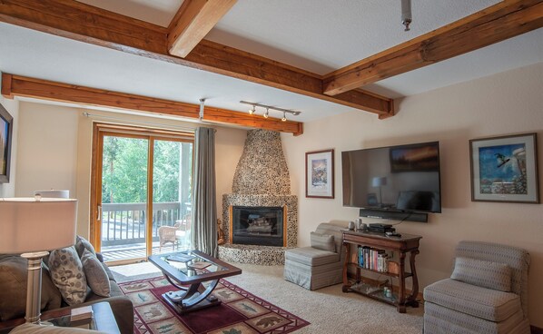 A cozy living room with a stone fireplace, a flat-screen TV, and comfortable seating.