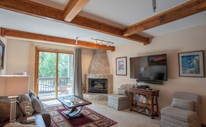 A cozy living room with a stone fireplace, a flat-screen TV, and comfortable seating.