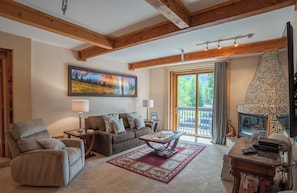 A cozy living room with a fireplace, a sofa, a coffee table, and a painting on the wall.