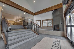 A staircase with a wooden handrail and metal balusters leading to a landing with a fireplace and a large window.