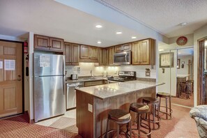 Une cuisine moderne avec des meubles en bois, des appareils en acier inoxydable et un îlot central doté de tabourets de bar.