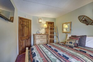 Une chambre à coucher avec un lit, une commode, une échelle et un miroir au mur.