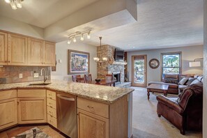A spacious kitchen with granite countertops, wooden cabinets, and a stone fireplace. - Wellington #3 (Townhome with Private Hot Tub) (Breckenridge)