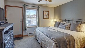 A bedroom with a bed, bedside lamp, ceiling fan, dresser, and a window with a view of a snowy landscape. - Wellington #3 (Townhome with Private Hot Tub) (Breckenridge)