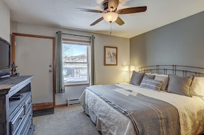 A bedroom with a bed, bedside lamp, ceiling fan, dresser, and a window with a view of a snowy landscape. - Wellington #3 (Townhome with Private Hot Tub) (Breckenridge)