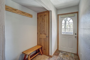 A hallway with a wooden bench, a wooden door, and a window with a view of trees. - Wellington #3 (Townhome with Private Hot Tub) (Breckenridge)