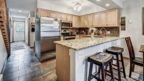 A modern kitchen with a central island, stainless steel appliances, and wooden cabinetry. - Wellington #3 (Townhome with Private Hot Tub) (Breckenridge)