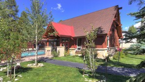Une cabane en rondins à deux étages, avec un toit rouge, une véranda et une piscine.
