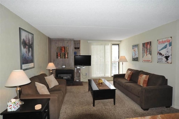 A living room with a sofa, a coffee table, a TV, and a fireplace. - Trail's End 509 Downtown Condos with on-site Hot Tub (Breckenridge)