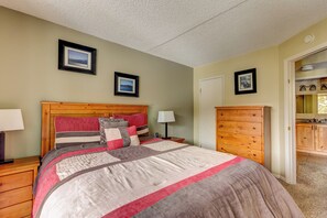 A bedroom with a wooden headboard, a large bed with a quilt, two bedside tables with lamps, and a wooden dresser.