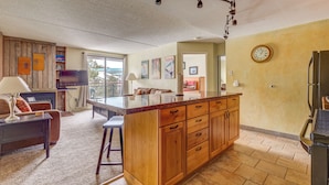 A spacious living area with a wooden island, a flat-screen TV, and a dining table. - Trail's End 509 Downtown Condos with on-site Hot Tub (Breckenridge)