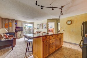 A spacious living area with a wooden island, a flat-screen TV, and a dining table.