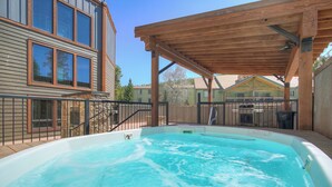 A backyard with a hot tub, wooden deck, and a covered patio area. - Atrium 207 Downtown Condos with on-site Hot Tub (Breckenridge)