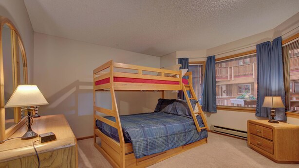 A bunk bed room with a desk, a lamp, and a window with curtains. - Atrium 207 Downtown Condos with on-site Hot Tub (Breckenridge)