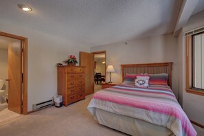 A bedroom with a bed, wooden dresser, and a mirror.