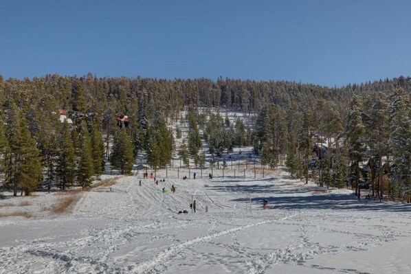 Une piste de ski enneigée, avec des arbres et des bâtiments en arrière-plan.
