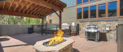 Un patio exterior con una chimenea de piedra, una parrilla y una zona de estar cubierta.