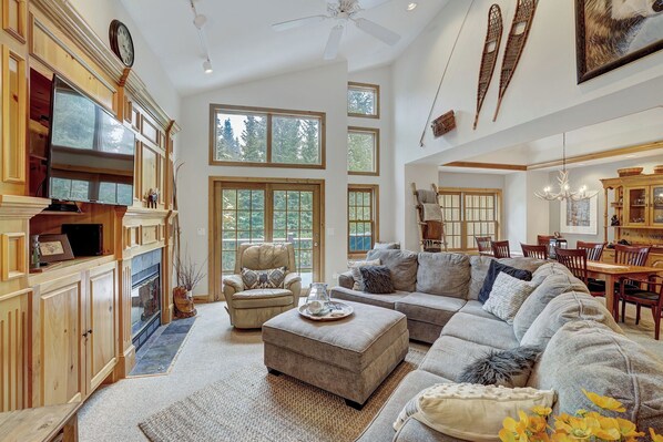 A spacious living room with a large sectional sofa, a fireplace, and a dining area with wooden furniture.
