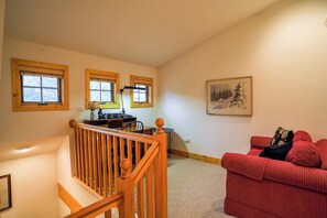 A staircase with wooden railings, a red couch, and a painting on the wall.