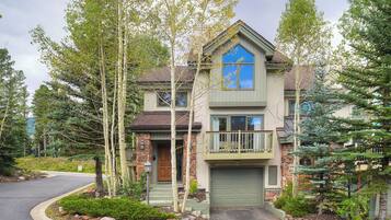 A two-story house with a stone facade, a blue front window, and a green garage door.