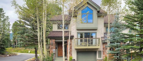 Une maison à deux étages avec une façade en pierre, une fenêtre bleue et une porte de garage verte.