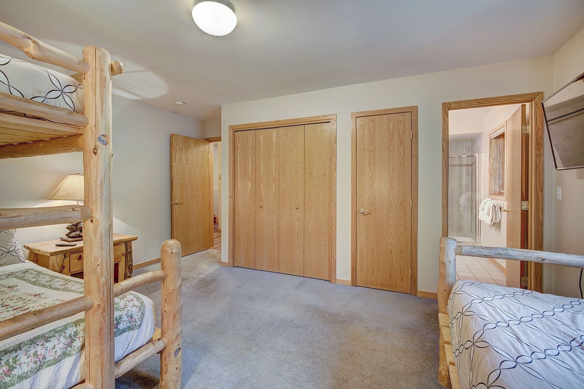 Een slaapkamer met stapelbedden, een houten garderobe en een douchehoek.