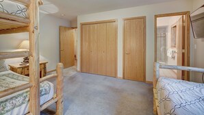 A bedroom with bunk beds, a wooden wardrobe, and a shower area. - Highlander 324 Townhome with Private Hot Tub (Breckenridge)