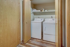 A laundry room with two stacked washers and dryers, wooden flooring, and a shelf above the dryers. - Highlander 324 Townhome with Private Hot Tub (Breckenridge)