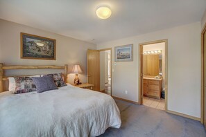 Ein Schlafzimmer mit einem großen Bett, einem Nachttisch mit Lampe, einem Holzkopfende und einem Gemälde an der Wand.