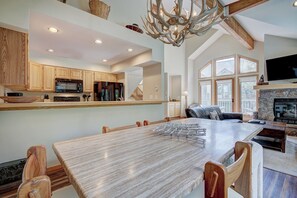 A spacious kitchen with wooden cabinets, a large dining table, and a chandelier. - Highlander 324 Townhome with Private Hot Tub (Breckenridge)