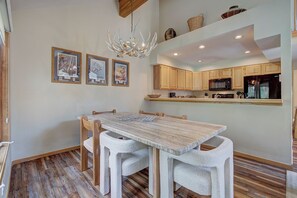 Ein Essbereich mit Holztisch und Stühlen, einer Kandelaber und gerahmten Bildern an der Wand.