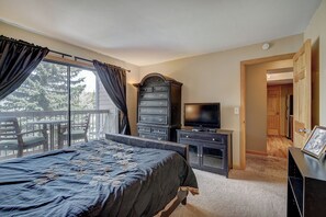 A bedroom with a bed, dresser, TV, and a balcony with a chair. - Longbranch 201 Condo with Pool & Hot Tub (Breckenridge)