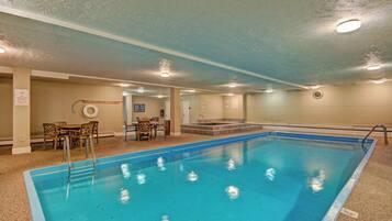 A swimming pool with a lifeguard chair, a table with chairs, and a clock on the wall.