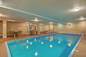 A swimming pool with a tiled deck, a lifeguard chair, and a table with chairs. - Longbranch 201 Condo with Pool & Hot Tub (Breckenridge)