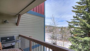 A balcony with a grill, a view of a snowy landscape, and a tree. - Longbranch 201 Condo with Pool & Hot Tub (Breckenridge)