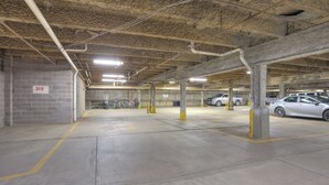 An underground parking garage with concrete pillars, marked parking spaces, and a few parked cars. - Longbranch 201 Condo with Pool & Hot Tub (Breckenridge)