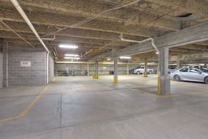 Un parking souterrain avec des piliers en béton, des emplacements de stationnement délimités et quelques voitures garées.