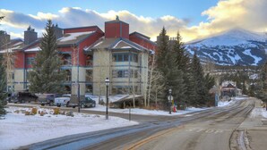 A hotel with a mountain view, a road with a stop sign, and snow on the ground. - Longbranch 201 Condo with Pool & Hot Tub (Breckenridge)
