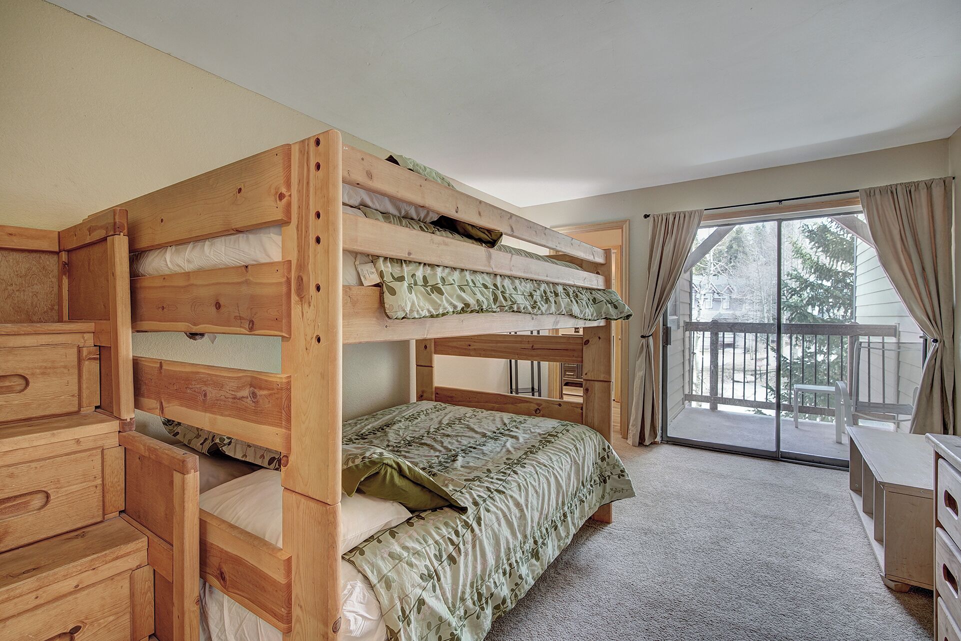 A bunk bed room with a sliding glass door leading to a balcony.