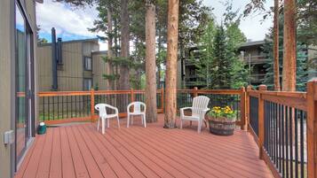 Une terrasse en bois avec des chaises blanches et un jardinier orné de fleurs.