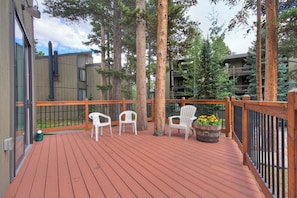 A wooden deck with white chairs and a planter with flowers. - Gold Camp II E87 Condo (Breckenridge)